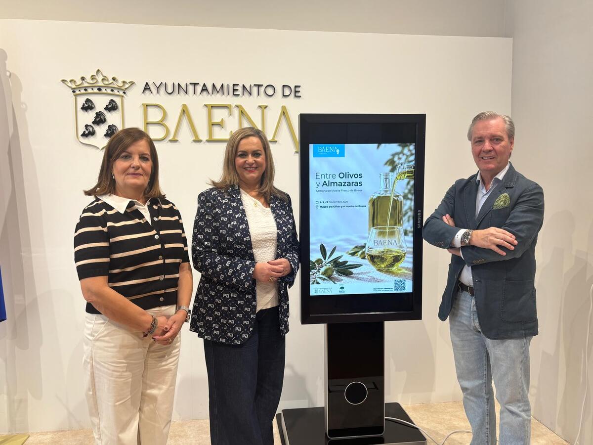 Tres personas posan junto a una pantalla táctil con un cartel sobre aceite de oliva, ante un rótulo del Ayuntamiento de Baena.