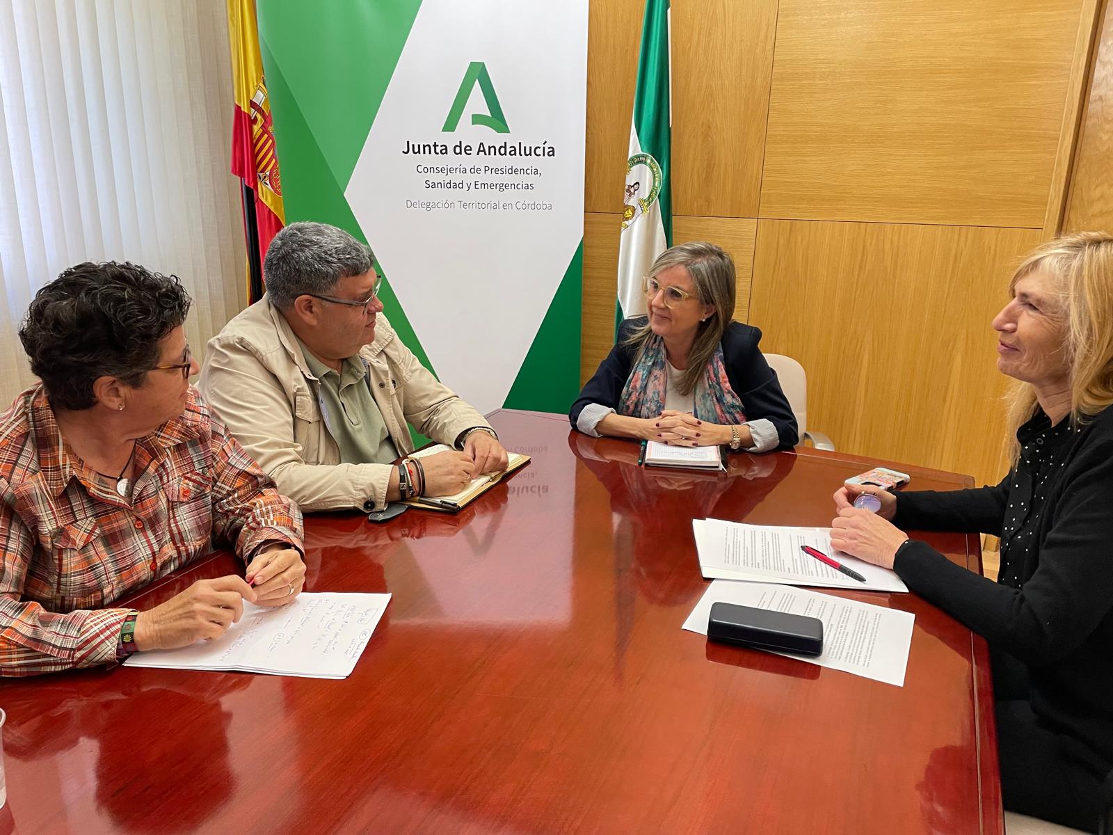 Cuatro personas sentadas alrededor de una mesa de reuniones con documentos, ante un cartel de la Junta de Andalucía.