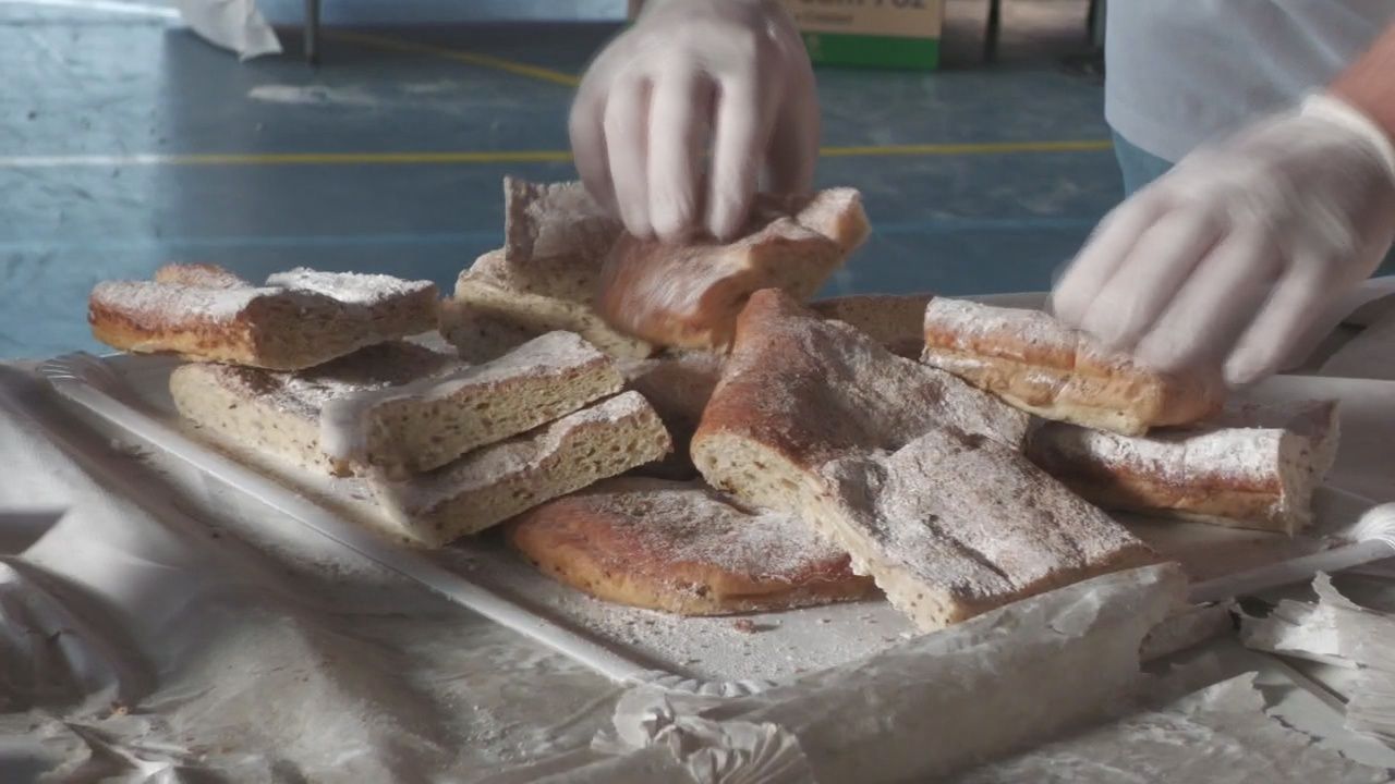 Manos con guantes blancos colocan trozos de masa espolvoreada con azúcar sobre una bandeja con papel de plata.