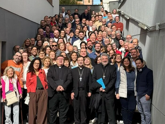 Un grupo numeroso de personas posa sonriente en una escalera exterior, con varias figuras con ropa clerical en primera fila.