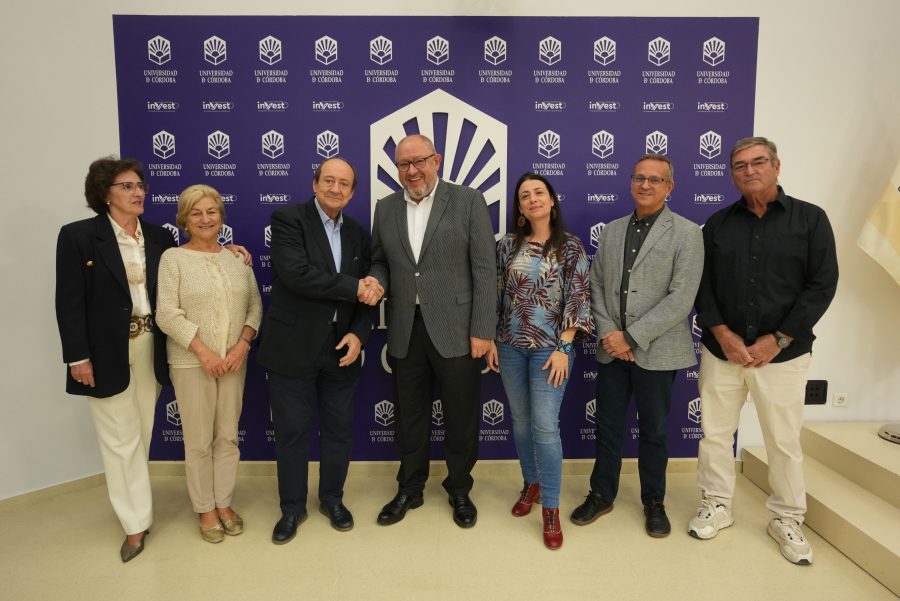 Seis personas posan de pie ante un panel morado con el logotipo de la Universidad de Córdoba, y dos de ellas se dan la mano.