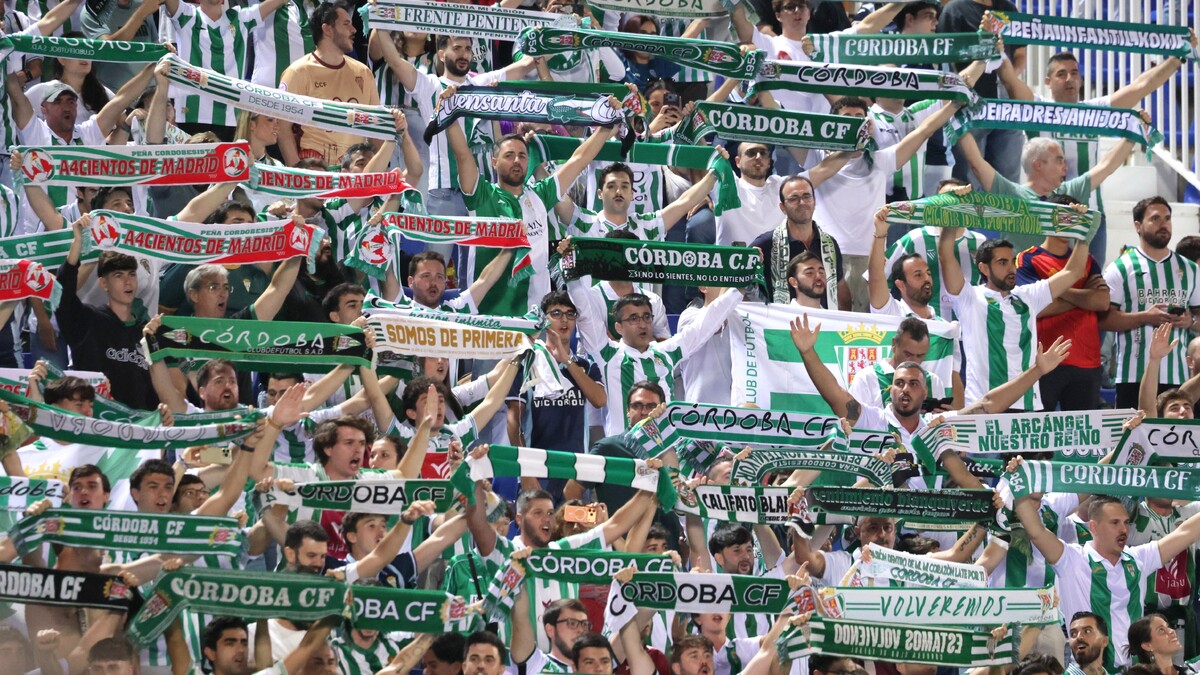 Una grada llena de aficionados con camisetas blancas y verdes que sostienen bufandas y pancartas del Córdoba CF.